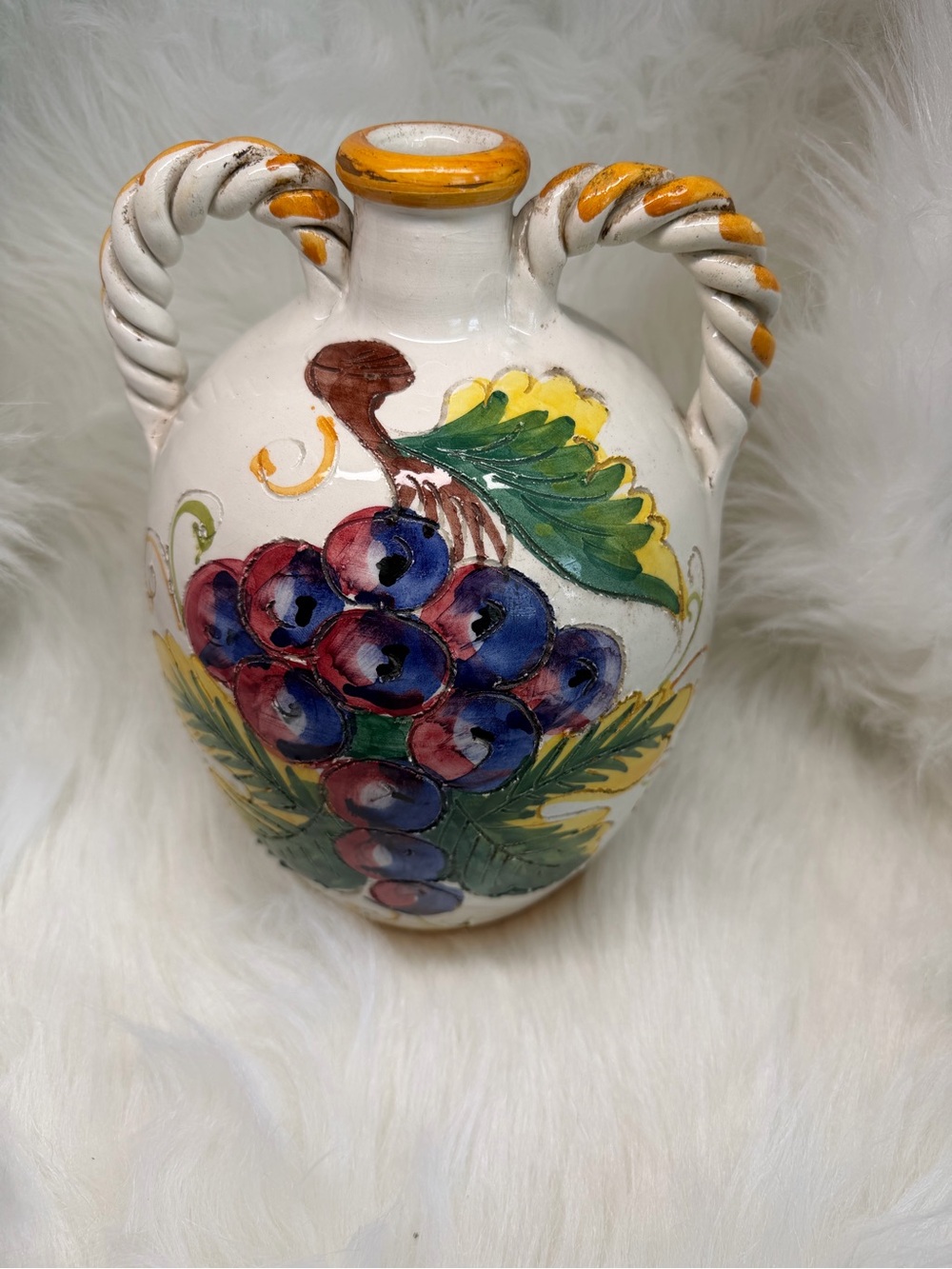 Hand-painted Italian ceramic jug with twisted handles and grape motif.